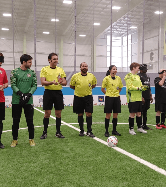A group from Soccability Canada standing in line on an indoor soccer field.