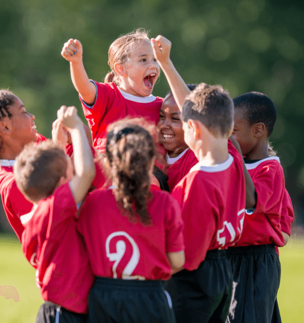 A kids soccer team celebrates together on a sunny day.