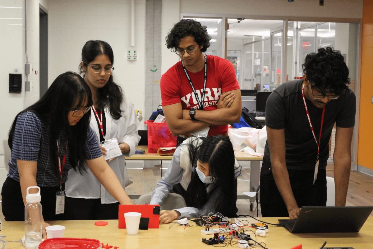 A group of York university STEM students work on a project at a boardroom table.